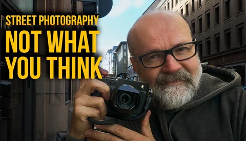 Bearded photographer holding compact camera on urban street with yellow text overlay