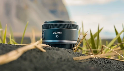 Canon RF 50mm lens positioned on textured ground with shallow depth of field