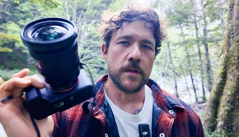 Photographer holding a wide-angle lens outdoors in a forest setting