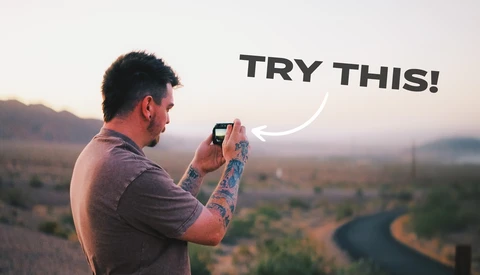 Photographer holding smartphone to capture landscape at golden hour