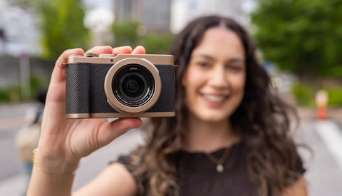 Woman holding a compact digital camera with black body and rose gold accents