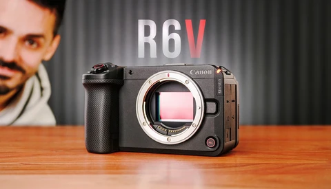 Canon R6V mirrorless camera displayed on wooden surface with portrait in background