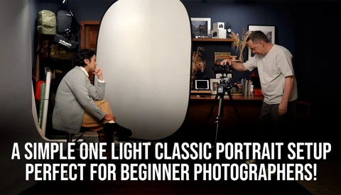 Photographer and subject during one-light portrait setup with large reflector and camera on tripod