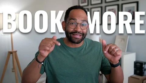 Man in green t-shirt and glasses pointing at camera with 'BOOK MORE' text overlay