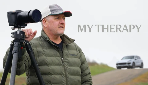 Photographer holding cinema camera on tripod shoulder rig with telephoto lens