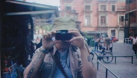 Photographer holding vintage film camera up to face in urban plaza