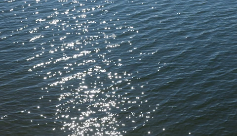 Sunlight glinting off calm ocean water creating sparkling reflections across the surface