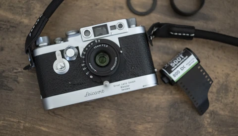 Voigtländer rangefinder camera with film canister and accessories on textured surface