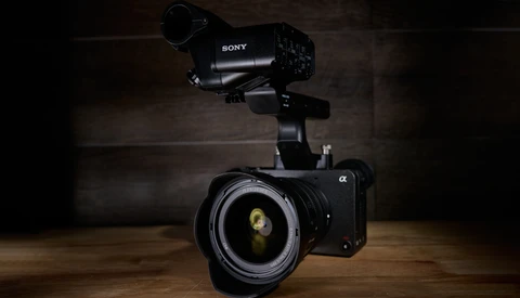 Sony mirrorless camera with telephoto lens and external microphone mounted on wooden surface