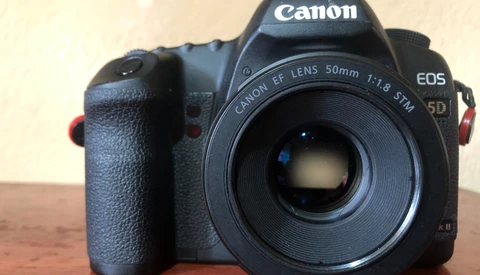 Canon EOS 5D DSLR with Canon EF 50mm f/1.8 STM lens mounted, displayed on wooden surface