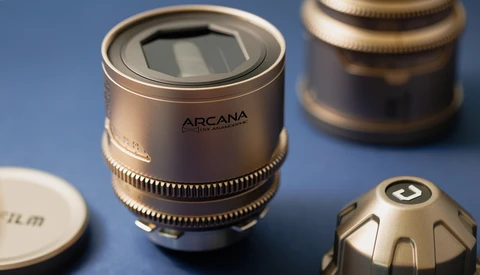 Arcana anamorphic lens with solar panel display and brass focus ring on blue surface