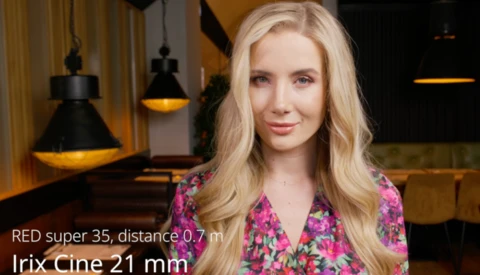 Portrait of woman with blonde wavy hair wearing magenta floral shirt against warm interior lighting