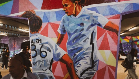 Large-scale mural of female athlete in dynamic pose with geometric background pattern