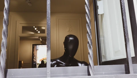 Black mannequin head displayed in storefront window behind white frames