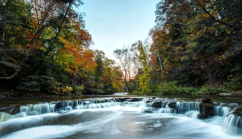 Cascading waterfall flowing through autumn woodland with smooth long-exposure water effect