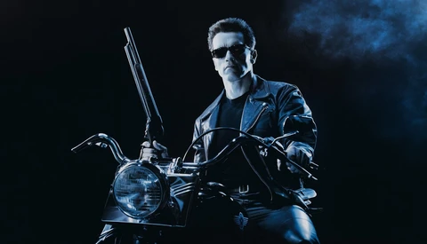Man in leather jacket and sunglasses sitting on motorcycle against dark blue background