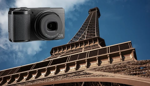 Ricoh GR compact camera overlaid on architectural photograph of Eiffel Tower