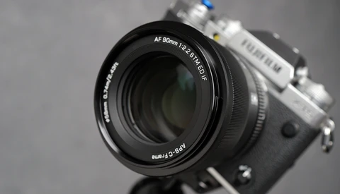 Fujifilm camera with AF 90mm f/2.4 R LM OIS lens mounted, shot against neutral gray background