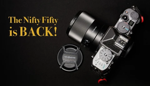 Mirrorless camera with telephoto lens and lens cap on black background with yellow text reading 'The Nifty Fifty is BACK!'