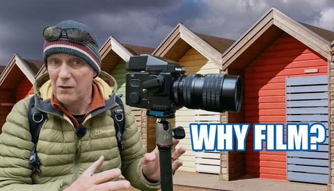 Filmmaker holding cinema camera with beach huts in background, with 'WHY FILM?' text overlay