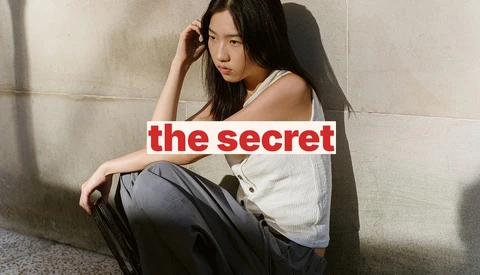 Woman sitting against concrete wall with text overlay reading 'the secret'