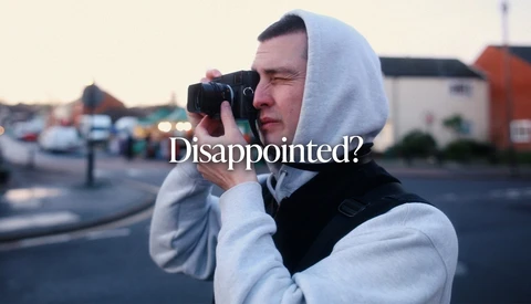 Person in white hoodie holding film camera to face with 'Disappointed?' text overlay