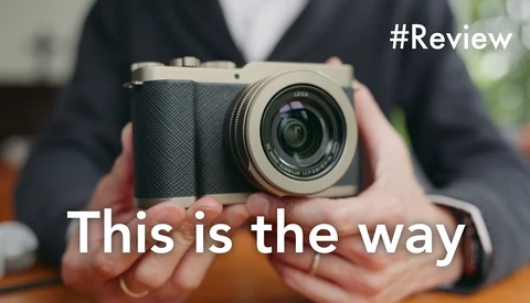 Person holding a mirrorless camera with a fixed prime lens, displayed for review