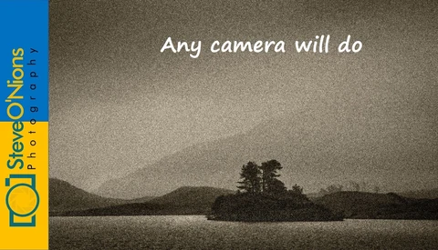 Monochromatic landscape with silhouetted trees on distant shoreline under grainy sky