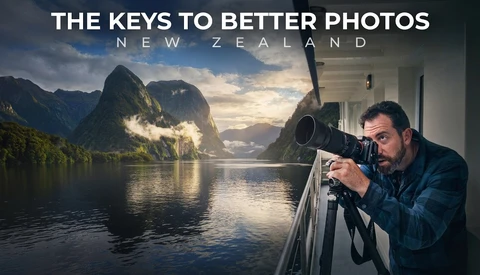 Photographer using telephoto lens on boat railing with Milford Sound fjord landscape behind