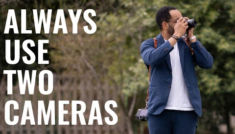 Photographer holding camera to face with text overlay reading 'ALWAYS USE TWO CAMERAS'