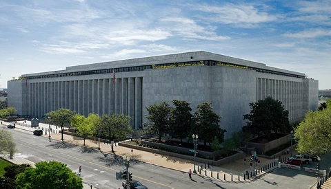 Modern concrete performing arts building with vertical ribbed facade and plaza seating