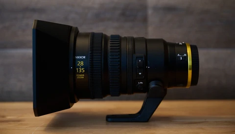 Nikon 28-135mm cinema lens with hood and support bracket on wooden surface