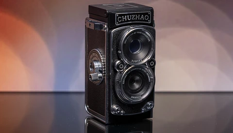 Chuzhao twin-lens reflex camera with dark leather covering displayed against warm and cool gradient lighting