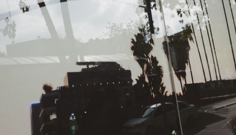 Double exposure of silhouetted buildings and palm trees overlaid with cloudy sky