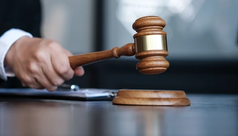 Judge striking wooden gavel on sound block during courtroom proceeding