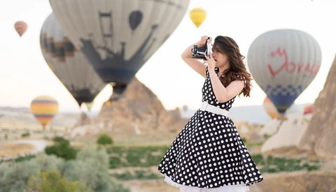 Woman in polka dot dress photographing hot air balloons in Cappadocia