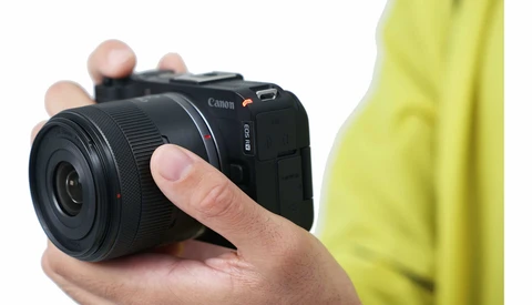 Hand holding a compact mirrorless camera with black body and lens