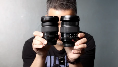 Photographer holding two vintage camera lenses up to face
