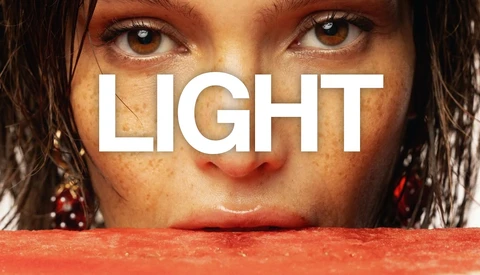 Close-up portrait of woman's face with word 'LIGHT' overlaid in white typography