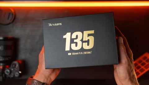 7Artisans 135mm F1.8 lens packaging being held up, displaying the lens specifications on the box