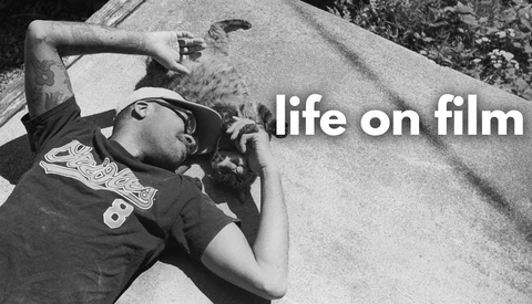 Black and white film photograph of person lying on concrete with text overlay reading 'life on film'