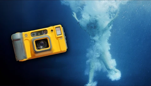 Yellow waterproof camera positioned above underwater scene with ascending air bubbles