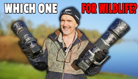 Wildlife photographer holding two telephoto lenses in outdoor setting with water and trees in background