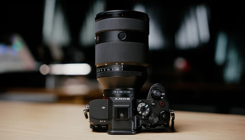 Mirrorless camera with telephoto zoom lens mounted on wooden surface with blurred interior background