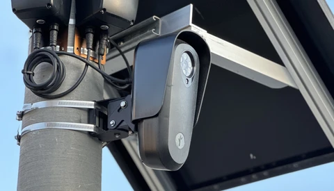 Street-mounted solar security camera and light fixture on concrete pole against clear sky