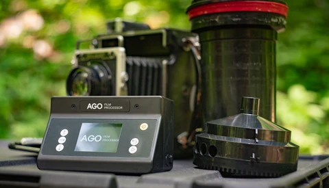 AGO film processor with digital control panel displayed alongside vintage large-format camera and film canister