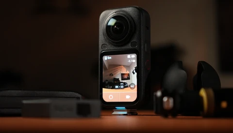Insta360 ONE RS action camera displayed on wooden surface with accessories