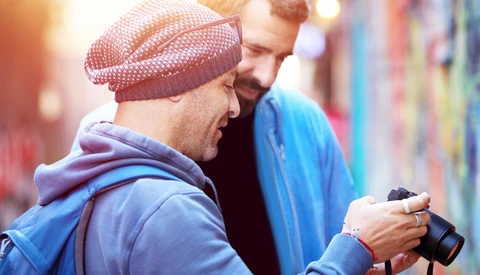 Two photographers reviewing images on a camera display outdoors
