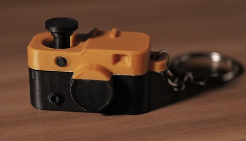 Yellow and black vintage toy camera with wind-up mechanism on wooden surface