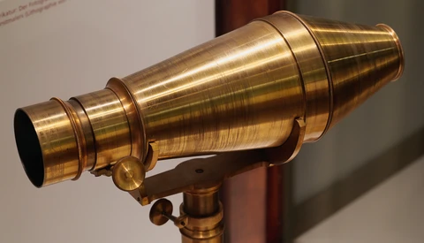 Vintage brass telescope with conical barrel and focusing mechanism mounted on tripod base